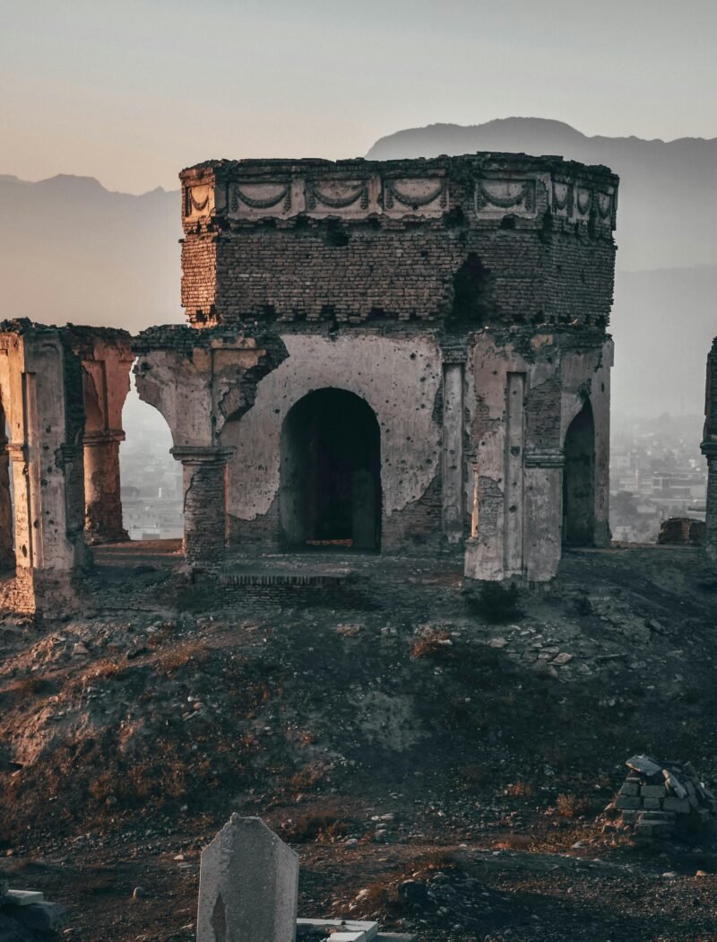 Aged ruins of King Nader Shah's tomb with a backdrop of Kabul city at dusk, displaying rich history.